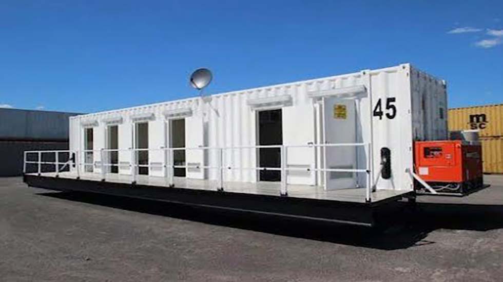 A large white shipping container converted into a modular building with HVAC systems, used as a functional workspace