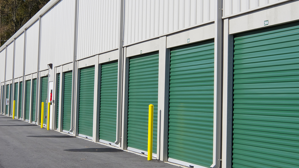 A row of green roller shed doors in a storage facility, designed for secure and accessible storage solutions