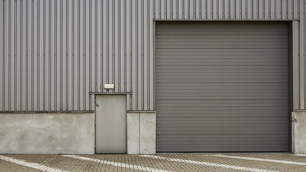 A solid metal door and a roller shutter door installed on a commercial building for secure access