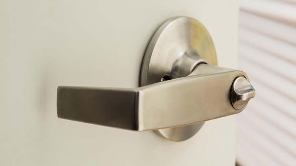 Close-up of a stainless steel door handle on a shed door, highlighting its durability and industrial design