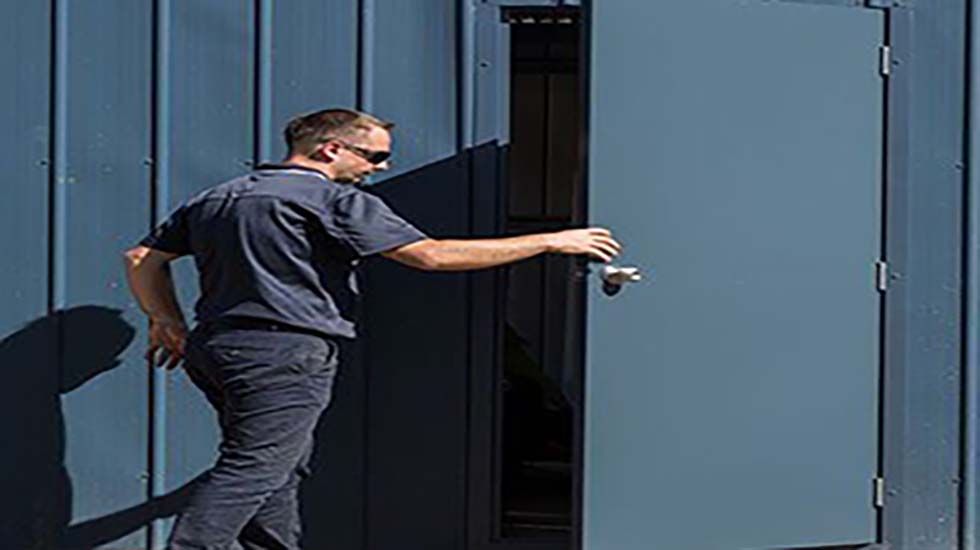 Man opening a blue personal access door designed for industrial and commercial use