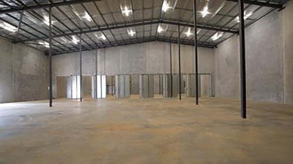 Spacious industrial tilt panel building with exposed concrete walls and large personal access doors for easy entry and exit.