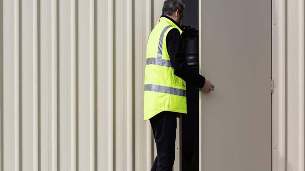 Worker in high-visibility gear opening a secure industrial door designed for durability and safety