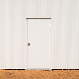 A robust white industrial door installed on a secure steel-clad facility.